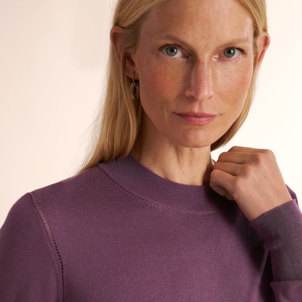 Woman wearing a purple fig color long sleeve sweater with navy wide leg pants