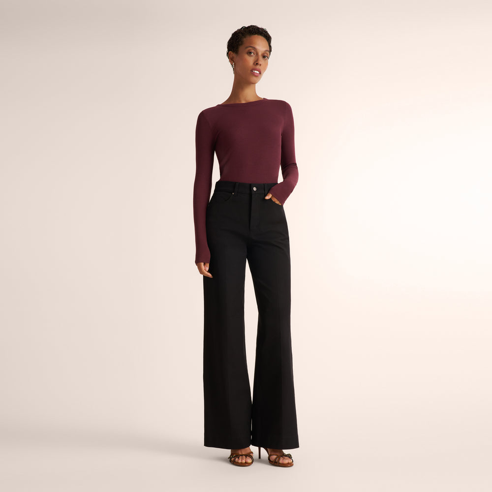Woman wearing an aubergine long sleeve t-shirt with wide leg black jeans