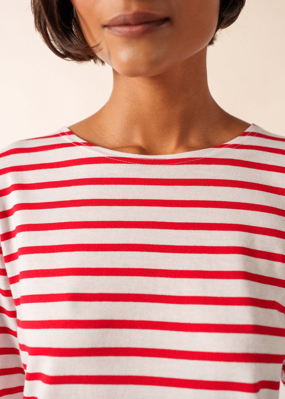 Red and white striped shirt worn by a person on a beige background
