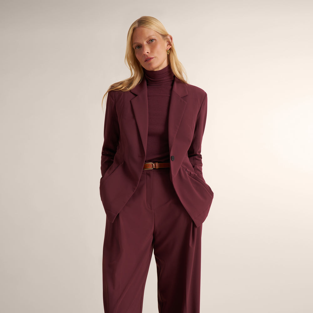 Woman wearing an aubgerine ribbed turtleneck with matching wide leg pants and matching blazer