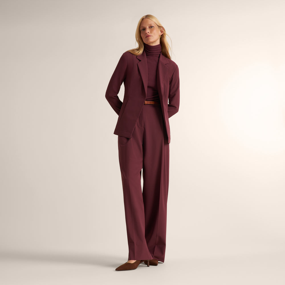 Woman wearing an aubgerine ribbed turtleneck with matching wide leg pants and matching blazer