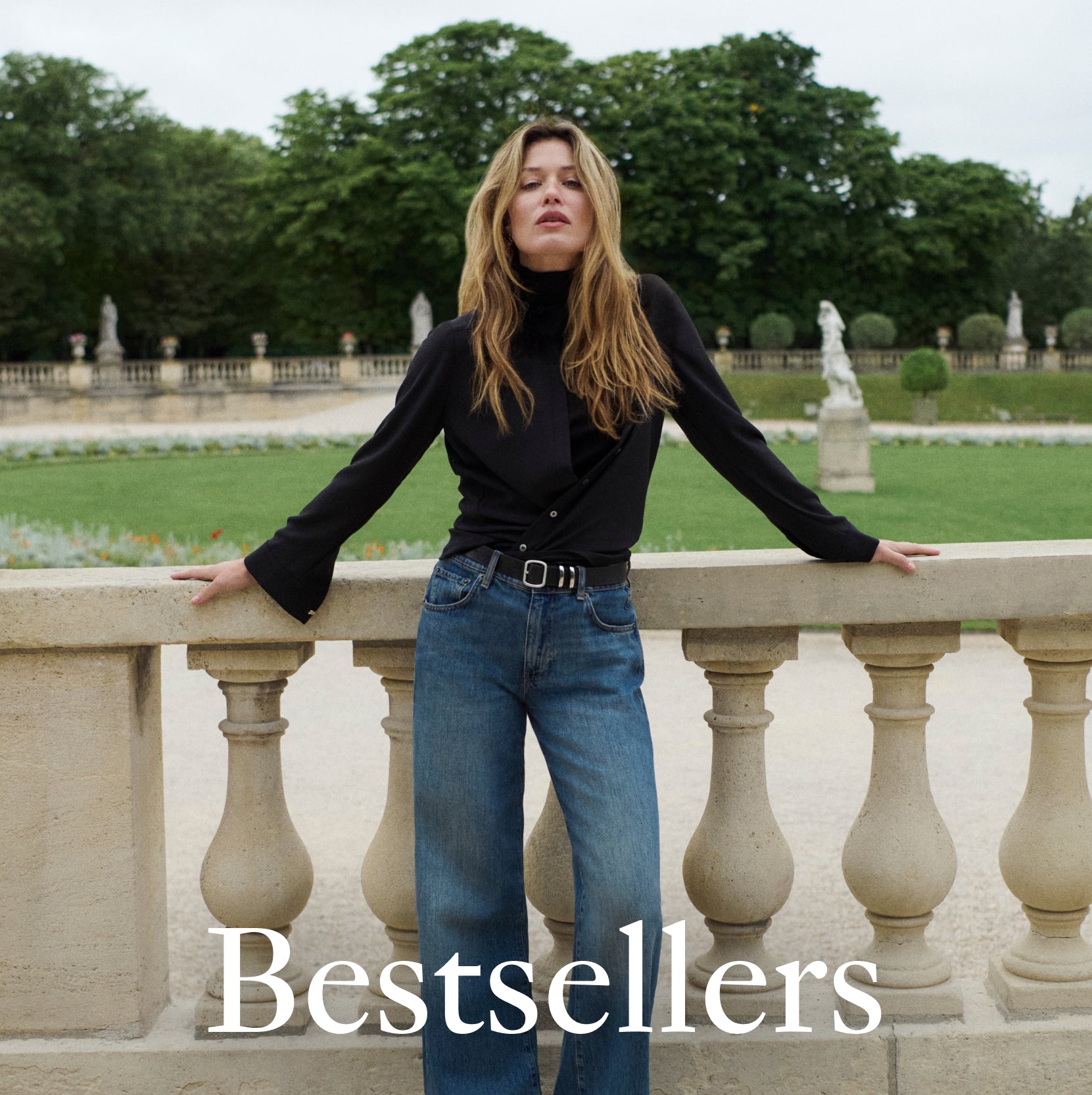 Image of a woman in a sculpture garden wearing a black turtleneck under a black long sleeve collared shirt with blue jeans. The word "Bestsellers" is overlaid