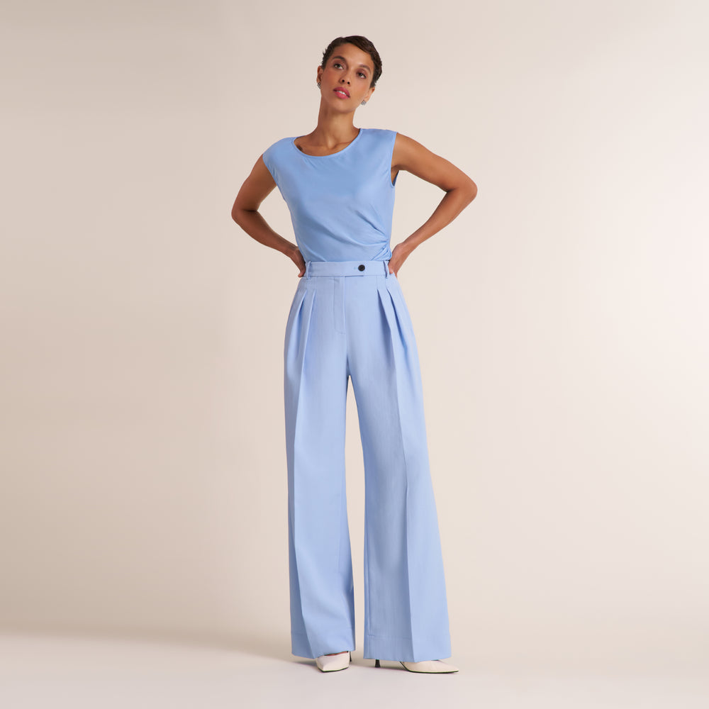 Woman wearing a light blue crew neck sleeveless top with light blue trouser pants