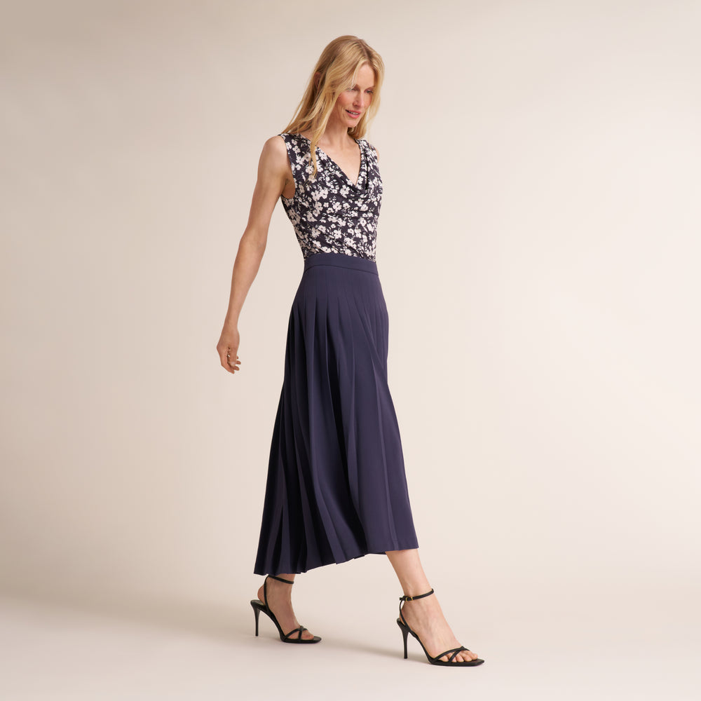 Woman wearing a a printed black and white top with a navy gray long skirt
