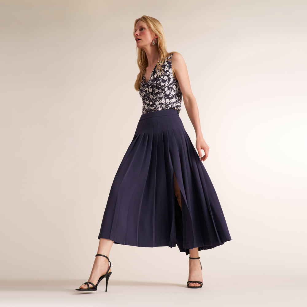 Woman wearing a a printed black and white top with a navy gray long skirt