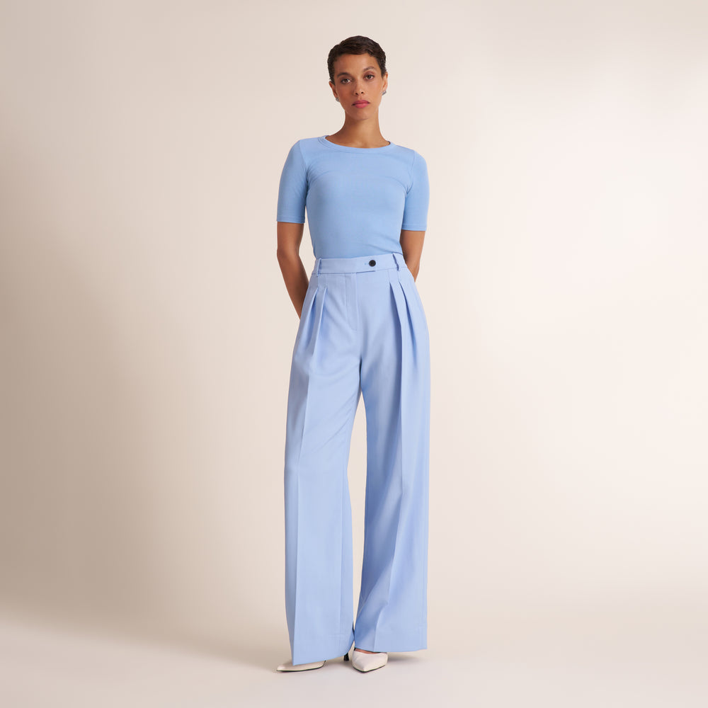 Woman wearing a crew neck, short sleeve t-shirt with light blue trouser pants