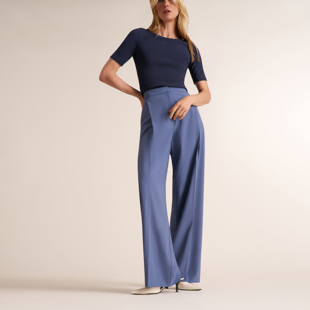 Woman wearing a navy crew neck, short sleeve t-shirt with blue trouser pants