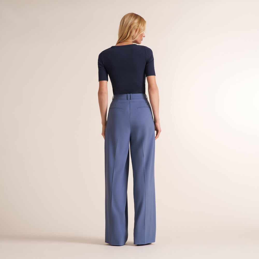 Woman wearing a navy crew neck, short sleeve t-shirt with blue trouser pants