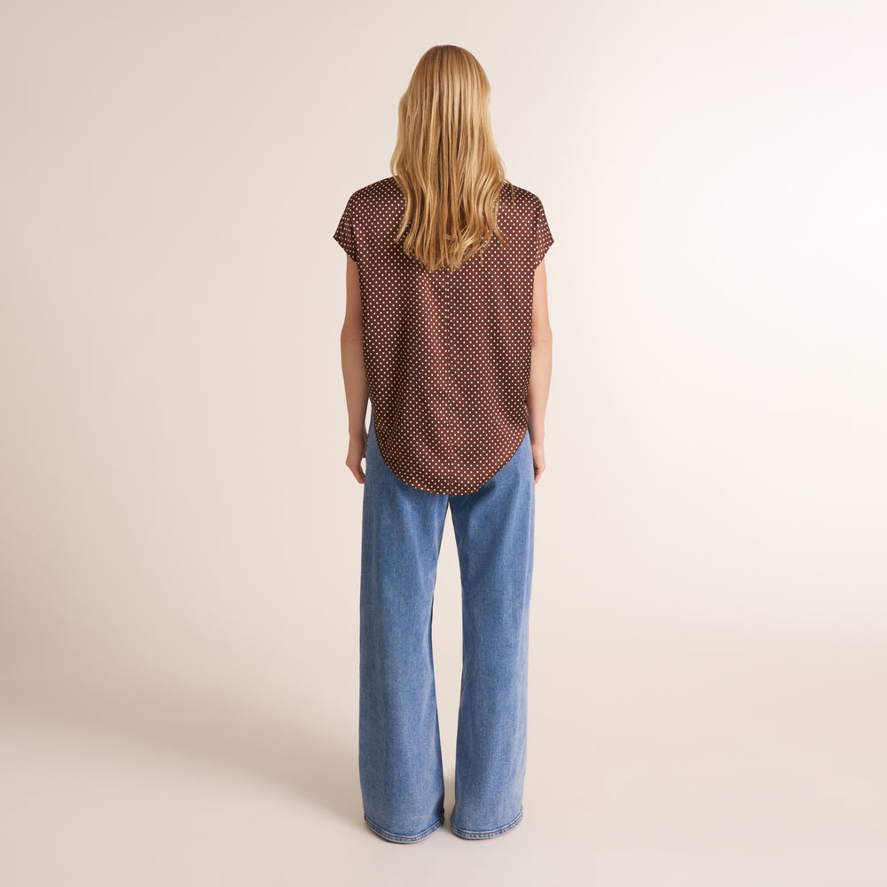 Woman wearing a pair of jeans with a cap sleeve top in a brown and white dot print