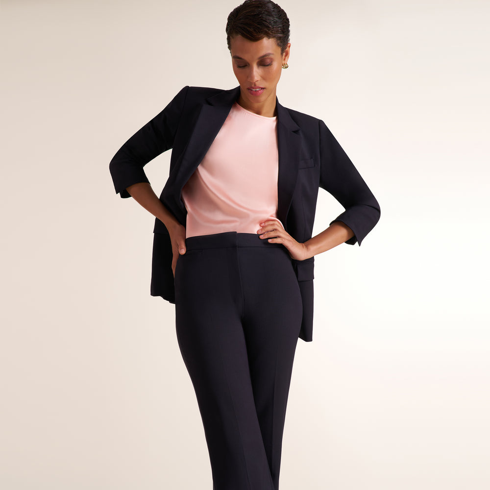 Woman wearing a flowy crew neck cap sleeve light pink silk charmeuse top with wide leg navy pants and matching blazer