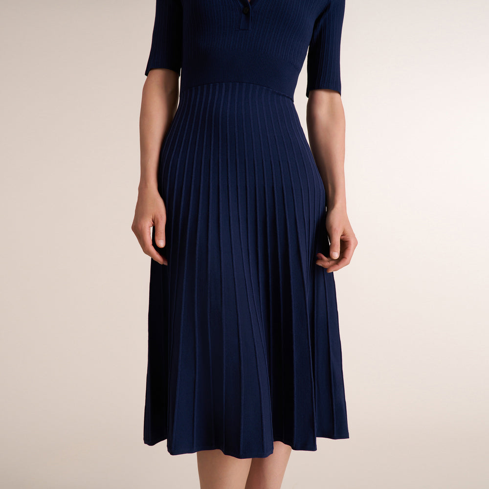 Woman wearing a three quarter sleeve dress with a midi pleated skirt