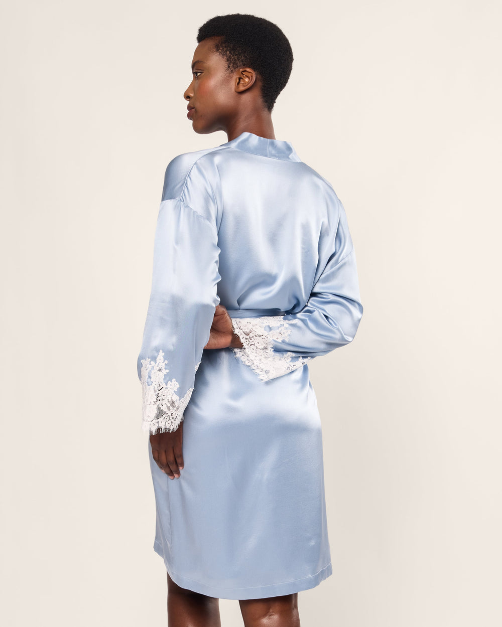 Light blue satin robe with lace cuffs worn by a person on a plain background