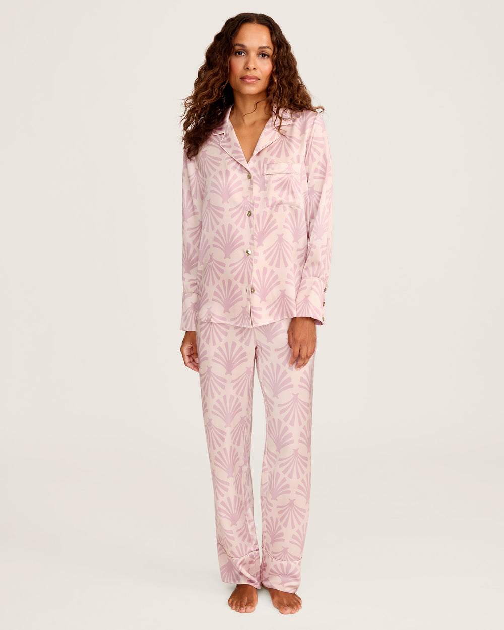 Woman wearing pink pajamas with a leaf pattern on a white background