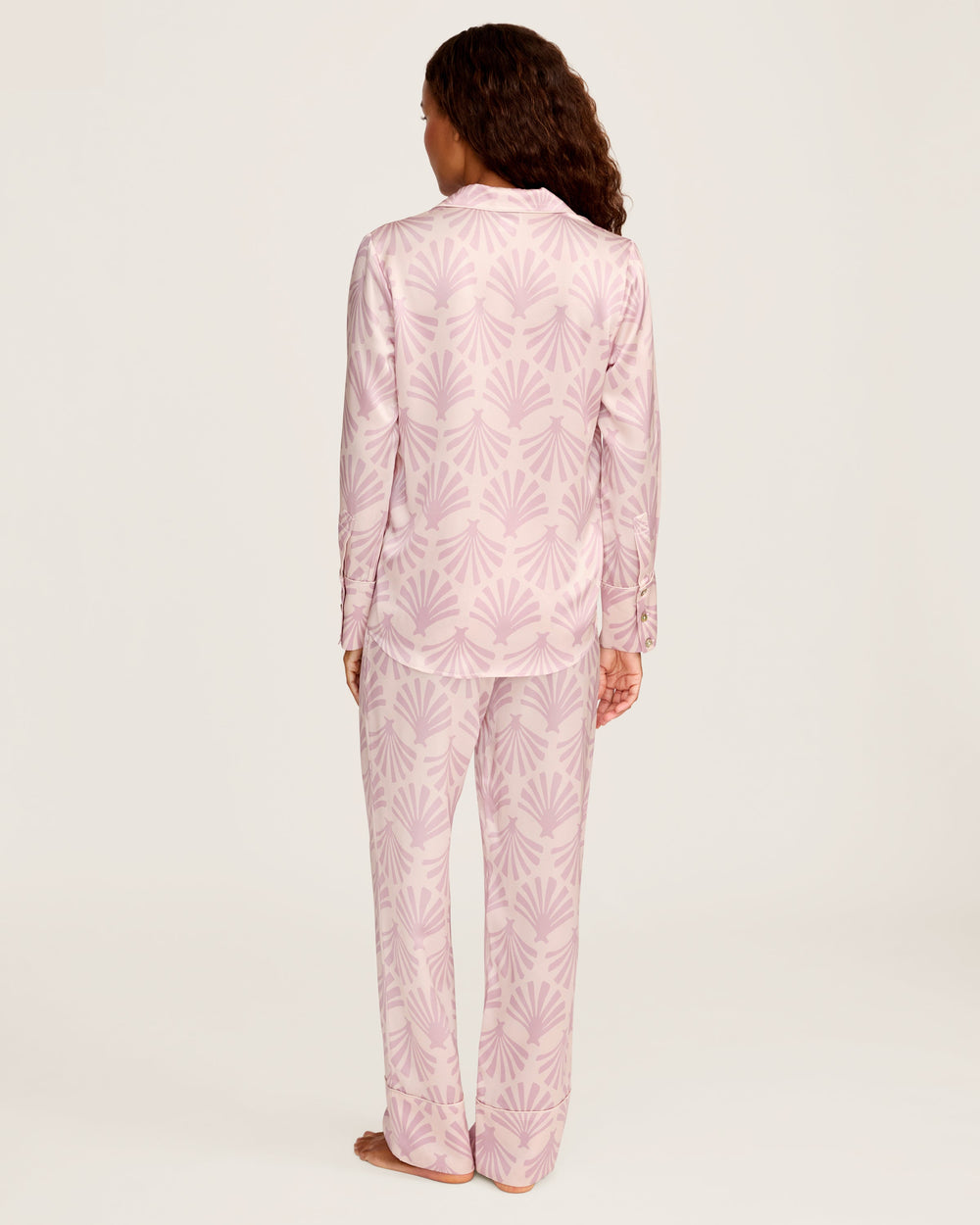 Person wearing pink pajama set with leaf pattern on a white background