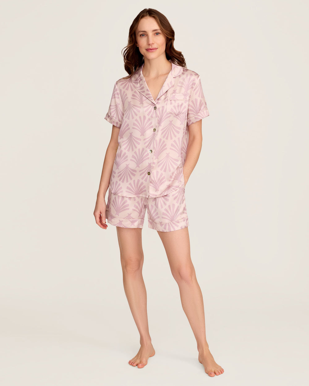 Woman wearing a pink floral pajama set on a white background