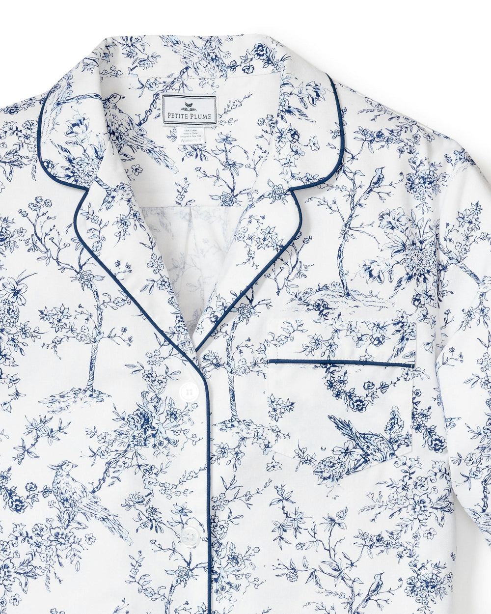 White pajama top with blue floral pattern and piping on a white background