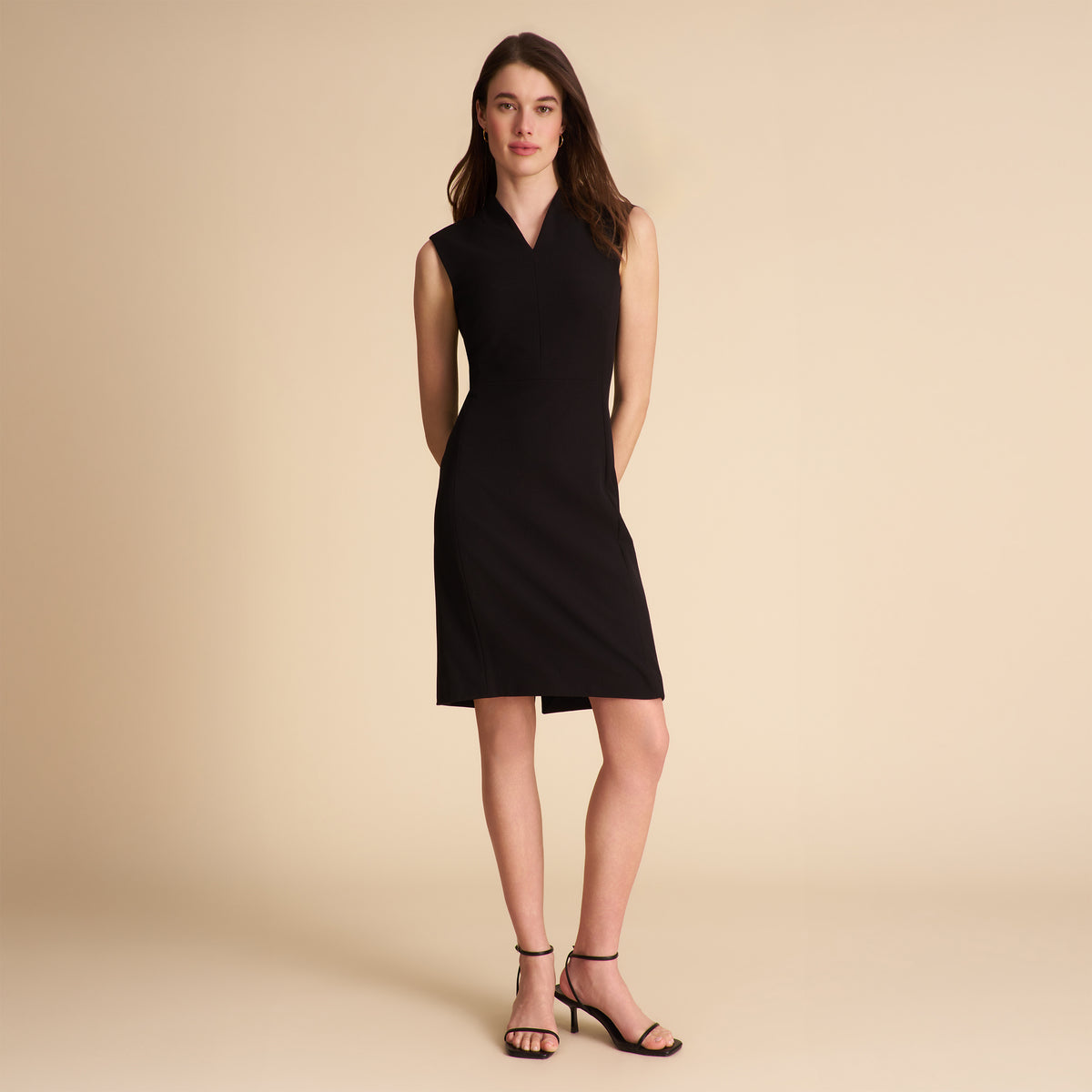 Woman wearing a black sleeveless dress on a beige background