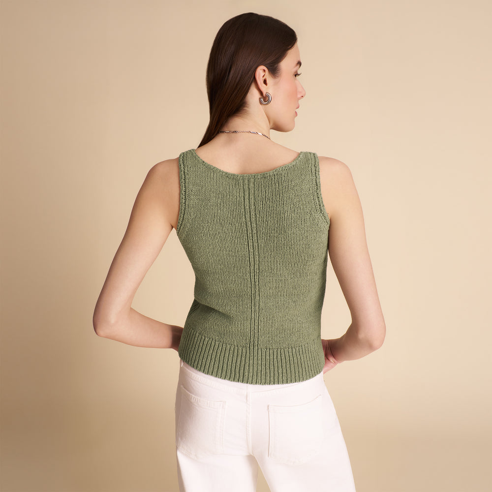 Woman wearing a green knitted sleeveless top against a beige background
