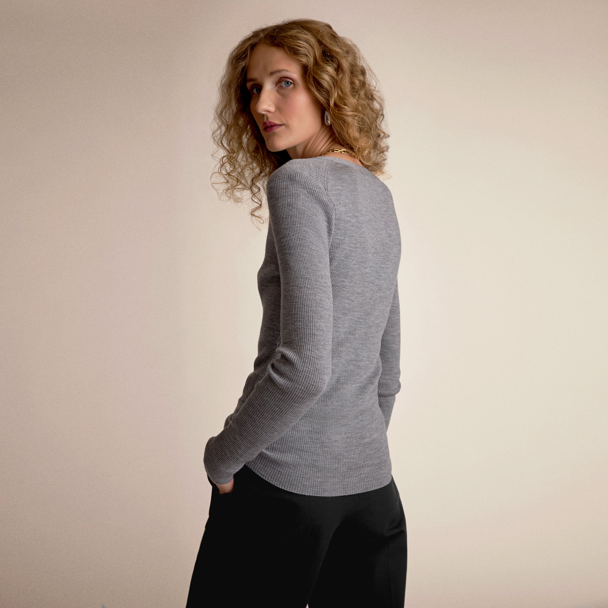 Woman wearing a gray sweater against a beige background