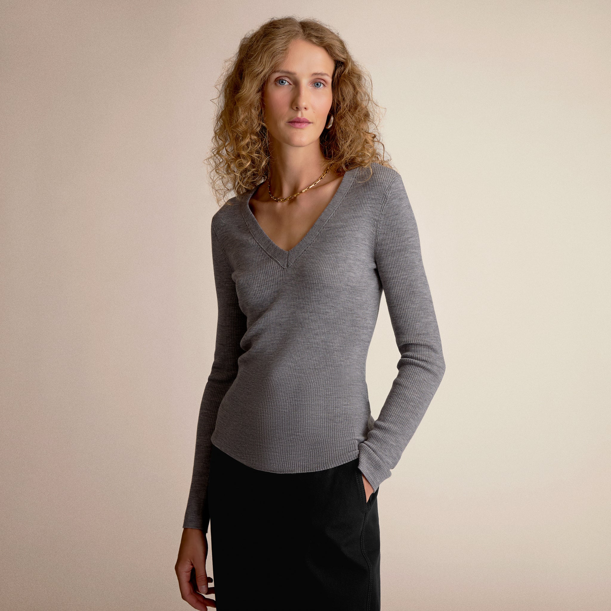 Woman wearing a gray sweater against a beige background 