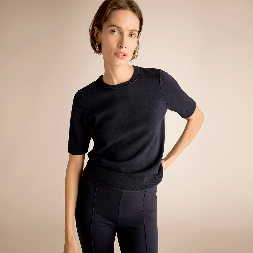 Woman wearing a black outfit against a beige background