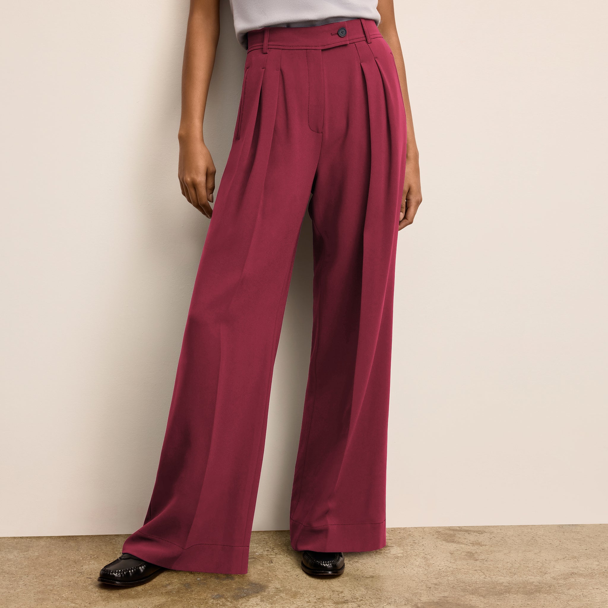 Person wearing maroon wide-leg pants against a beige wall. 