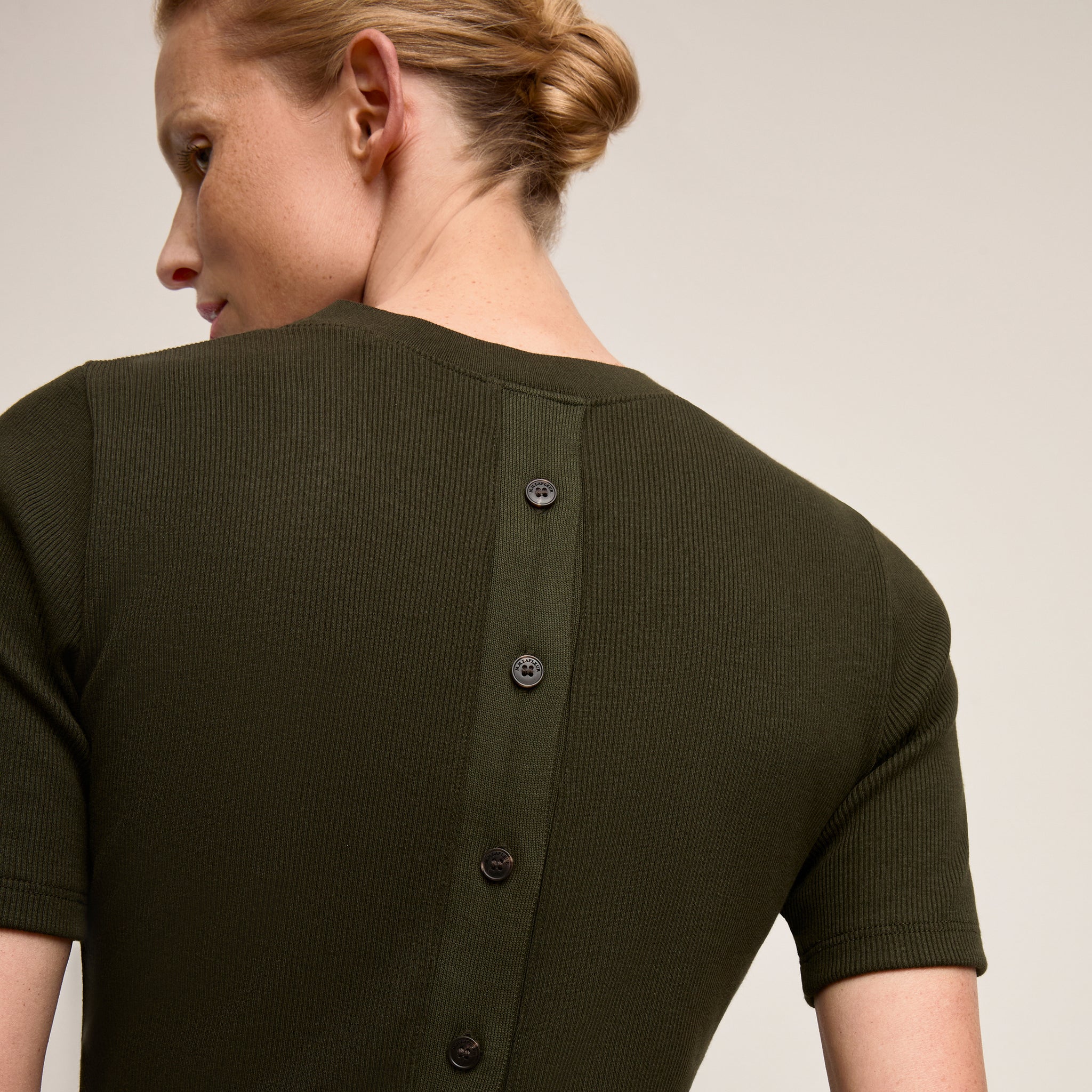 Green ribbed sweater with buttons on a plain background