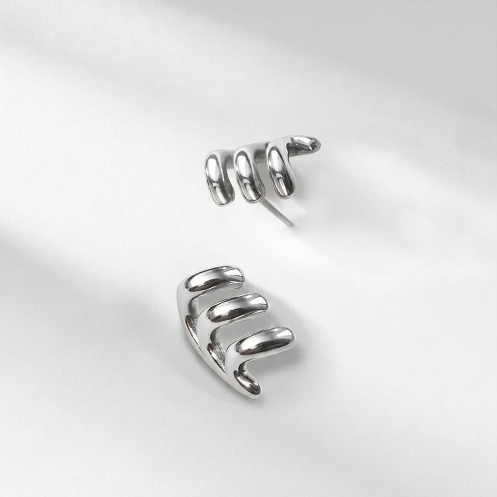 A pair of polished silver spiral ear cuffs displayed on a clean, light gray fabric background.