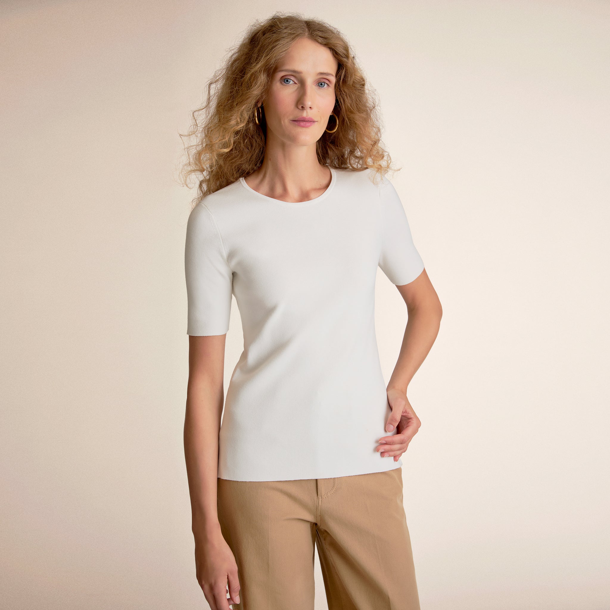 Front image of a woman standing wearing the choe top in ivory