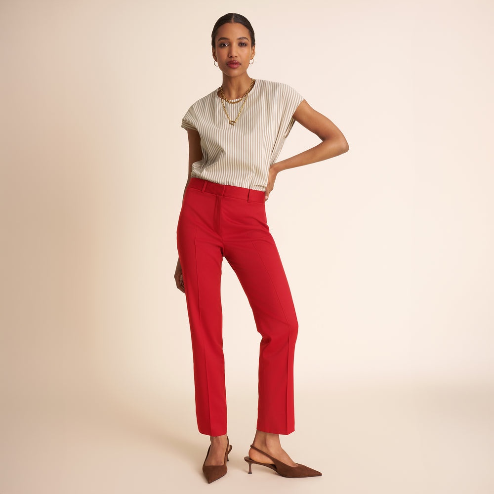 Woman wearing a white top and red pants on a beige background