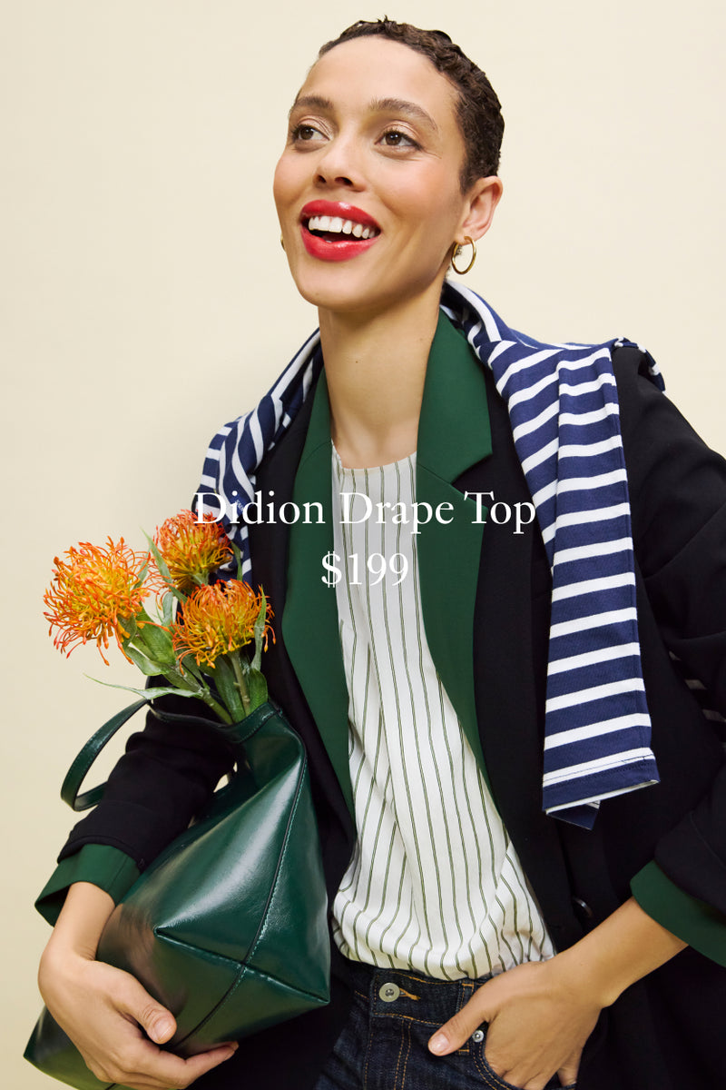 Woman wearing a striped scarf and holding flowers, with text overlay about a dress top.

DIDION DRAPE TOP
$199