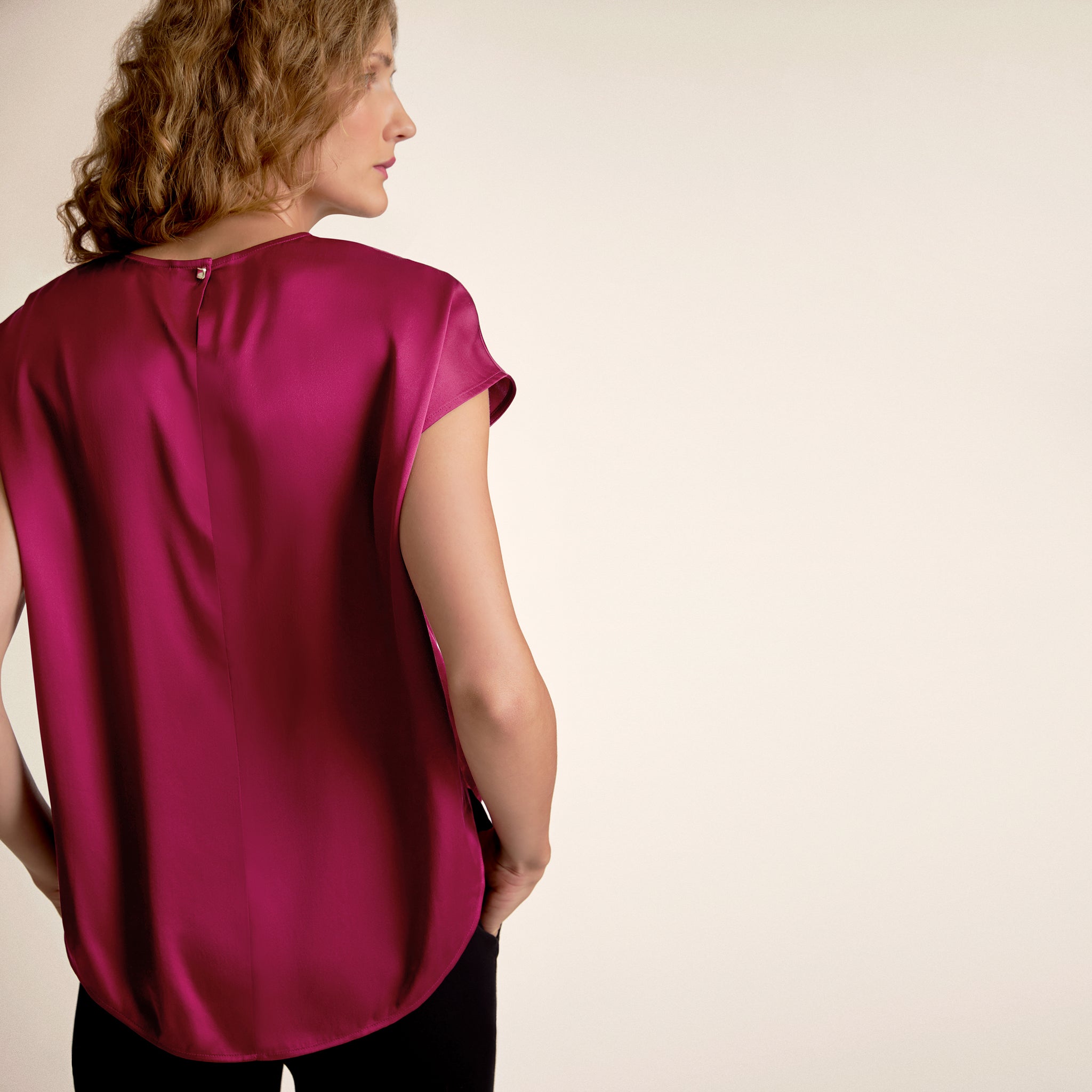Woman wearing a magenta blouse against a beige background