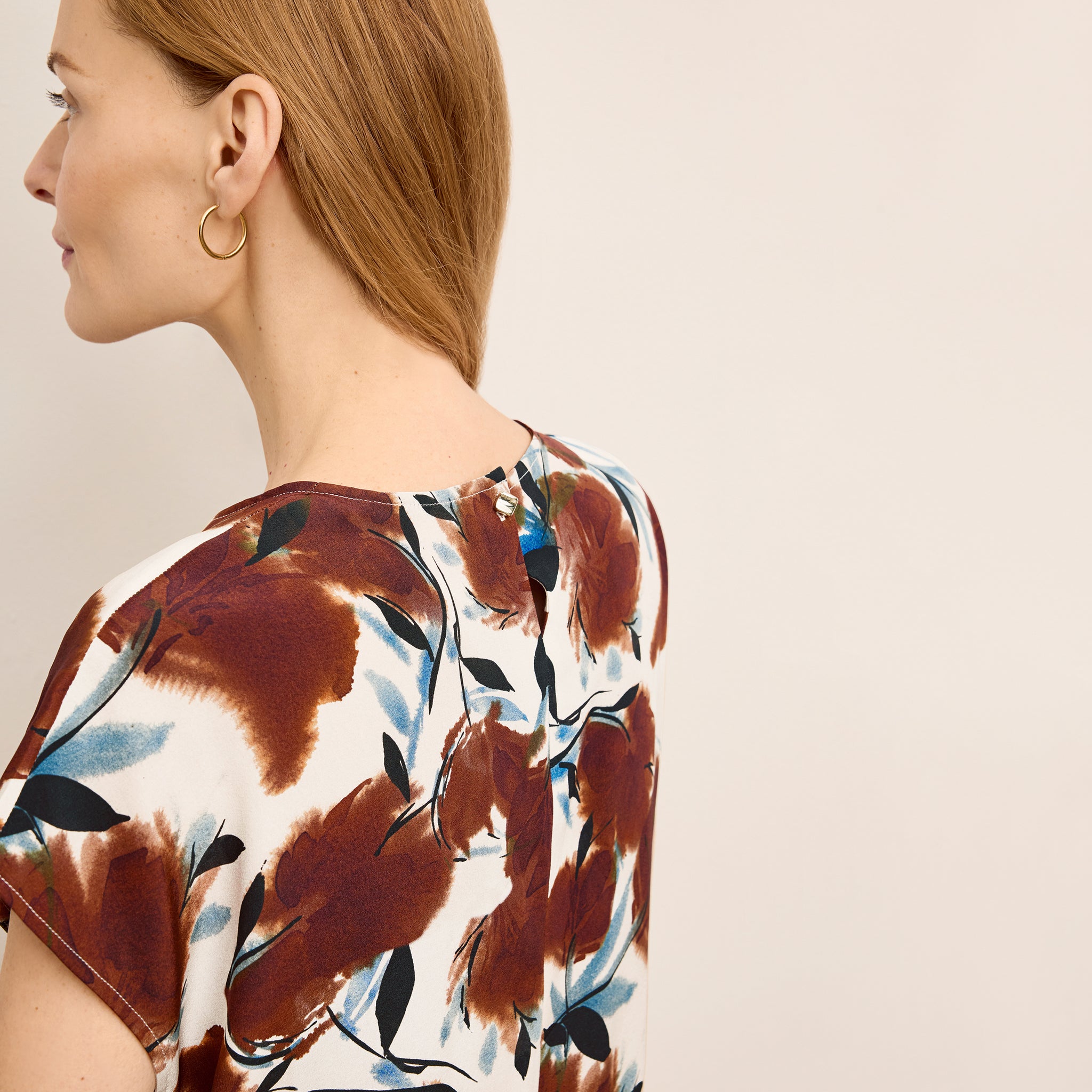 Woman wearing a floral blouse with a neutral background