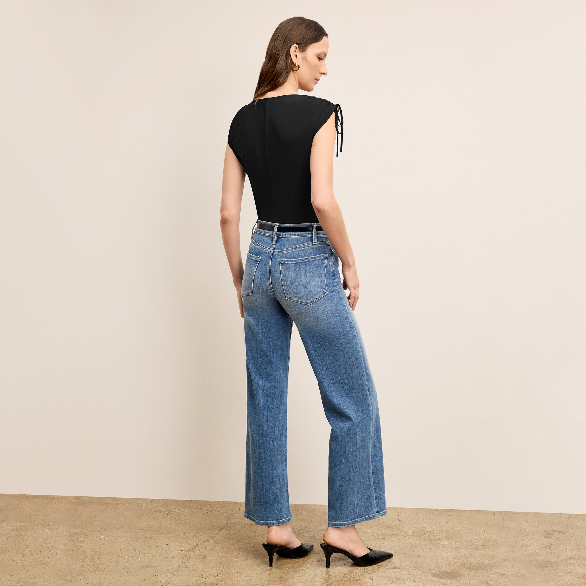 Back image of a woman wearing the Dotty Top in Black with denim jeans