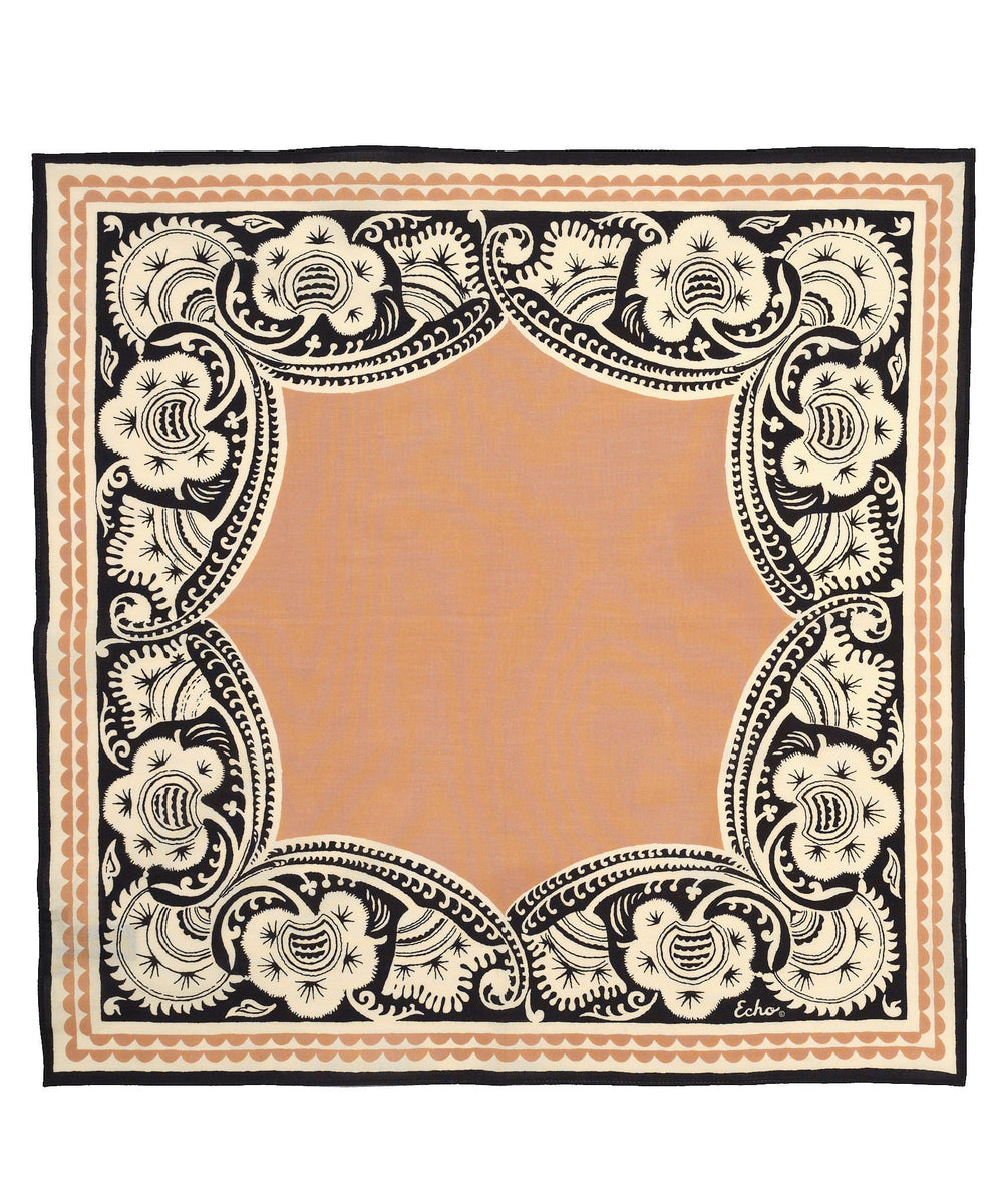A square scarf with a warm peach center and an ornate black and cream floral border, shown flat against a white background.