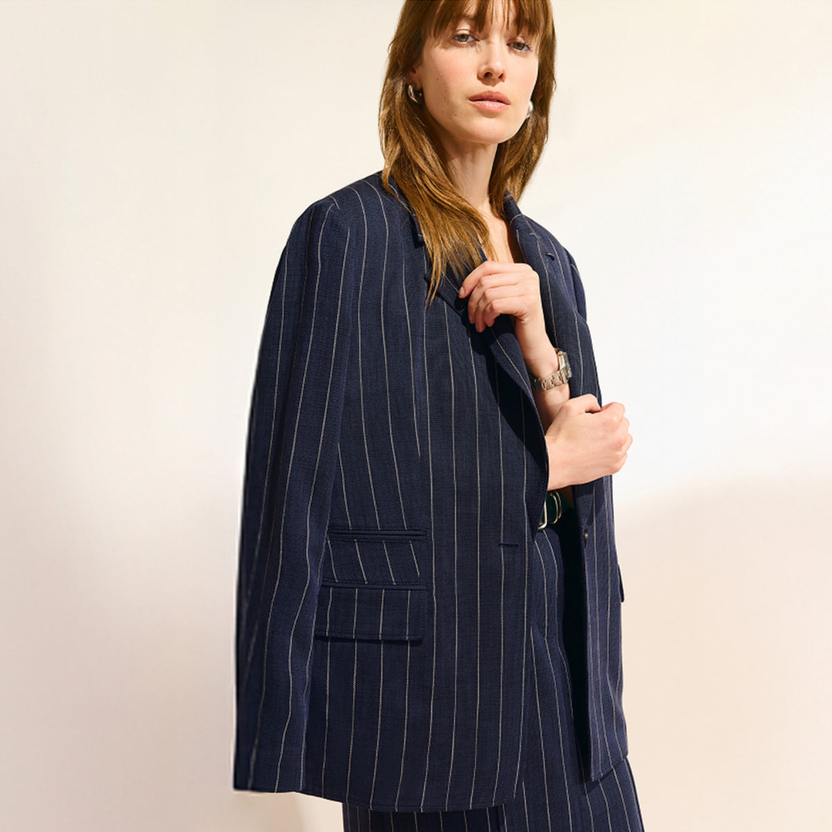 Woman wearing a navy pinstripe suit against a plain background