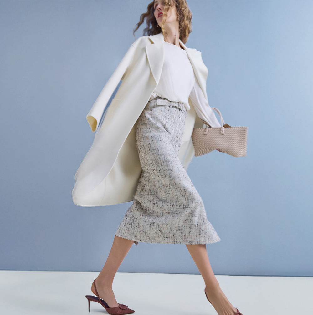 Woman wearing a gray textured suit with a white top on a beige background