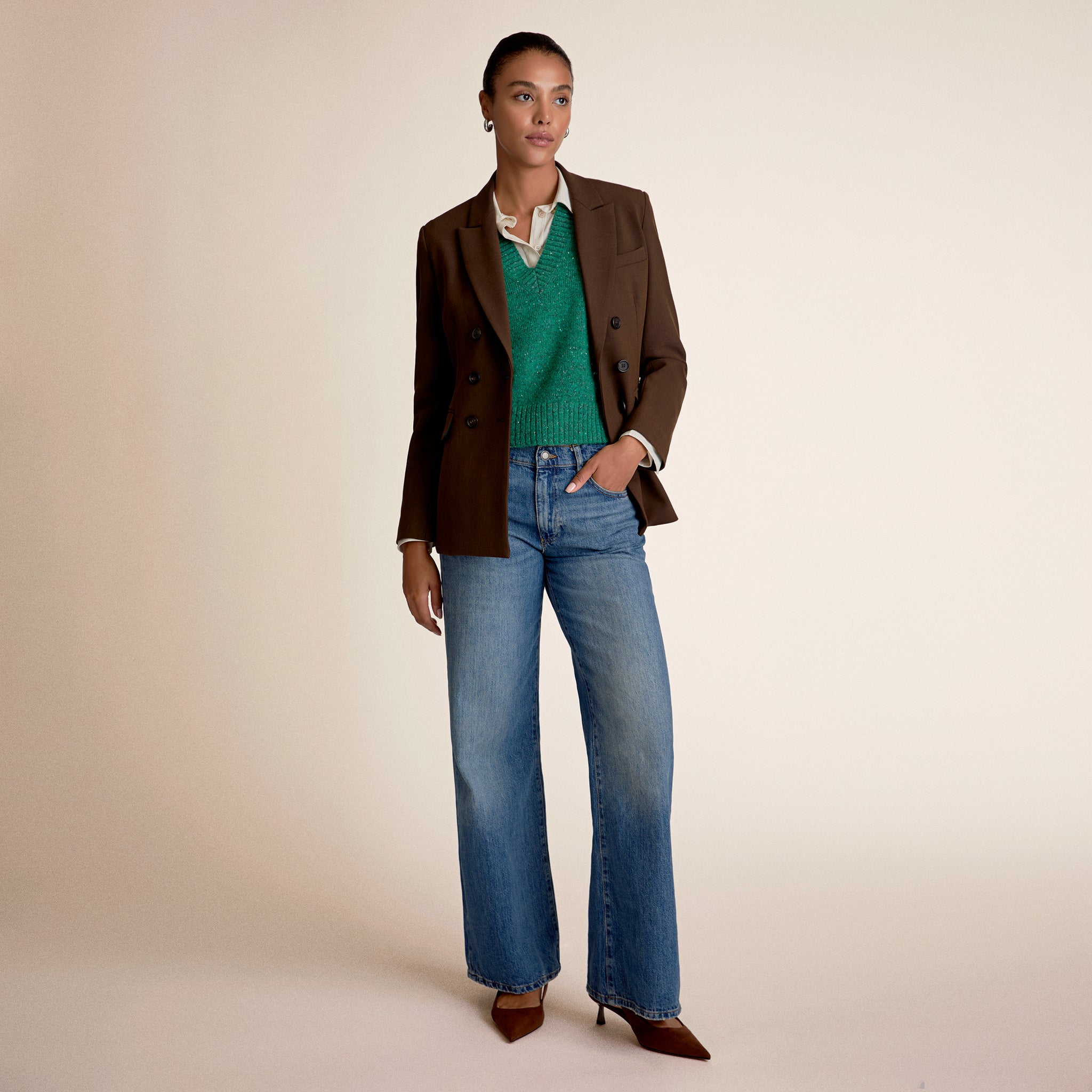 Woman wearing green sweater vest and a brown blazer 