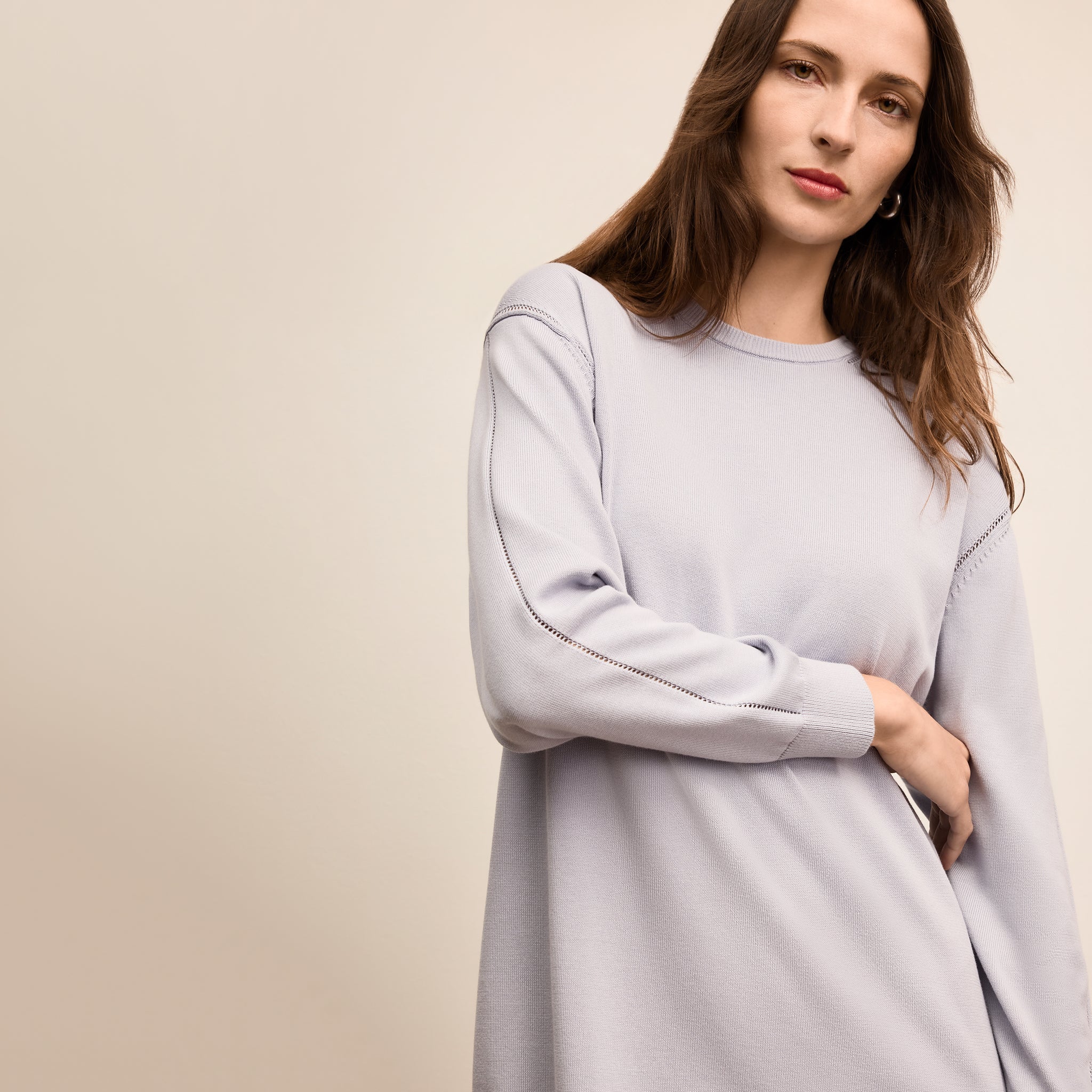Woman wearing a light gray dress against a beige background