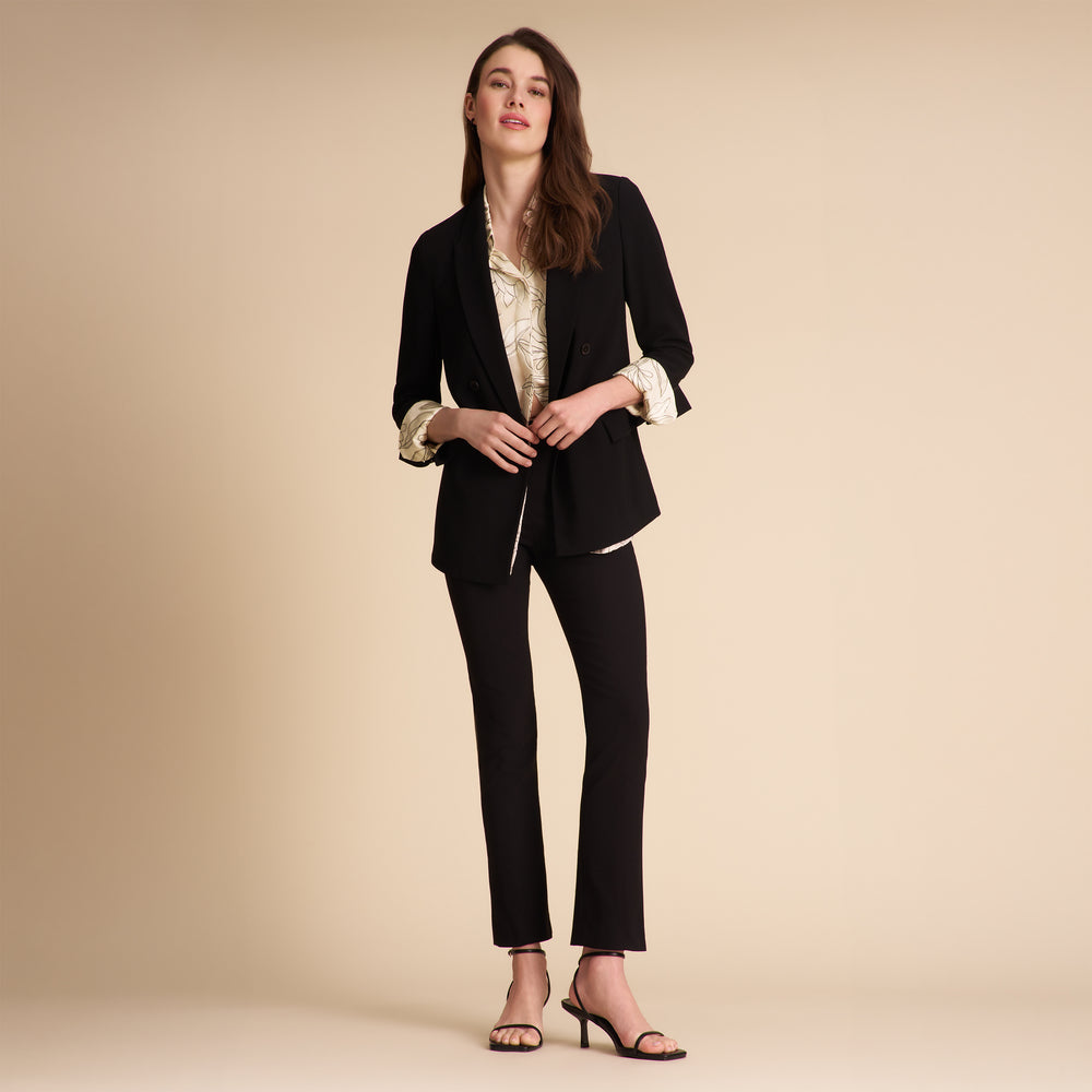 Person wearing black pants and a patterned top on a beige background
