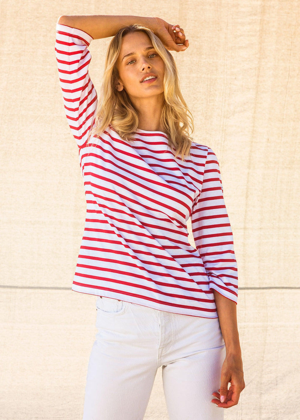 Woman wearing a red and white striped shirt against a beige wall