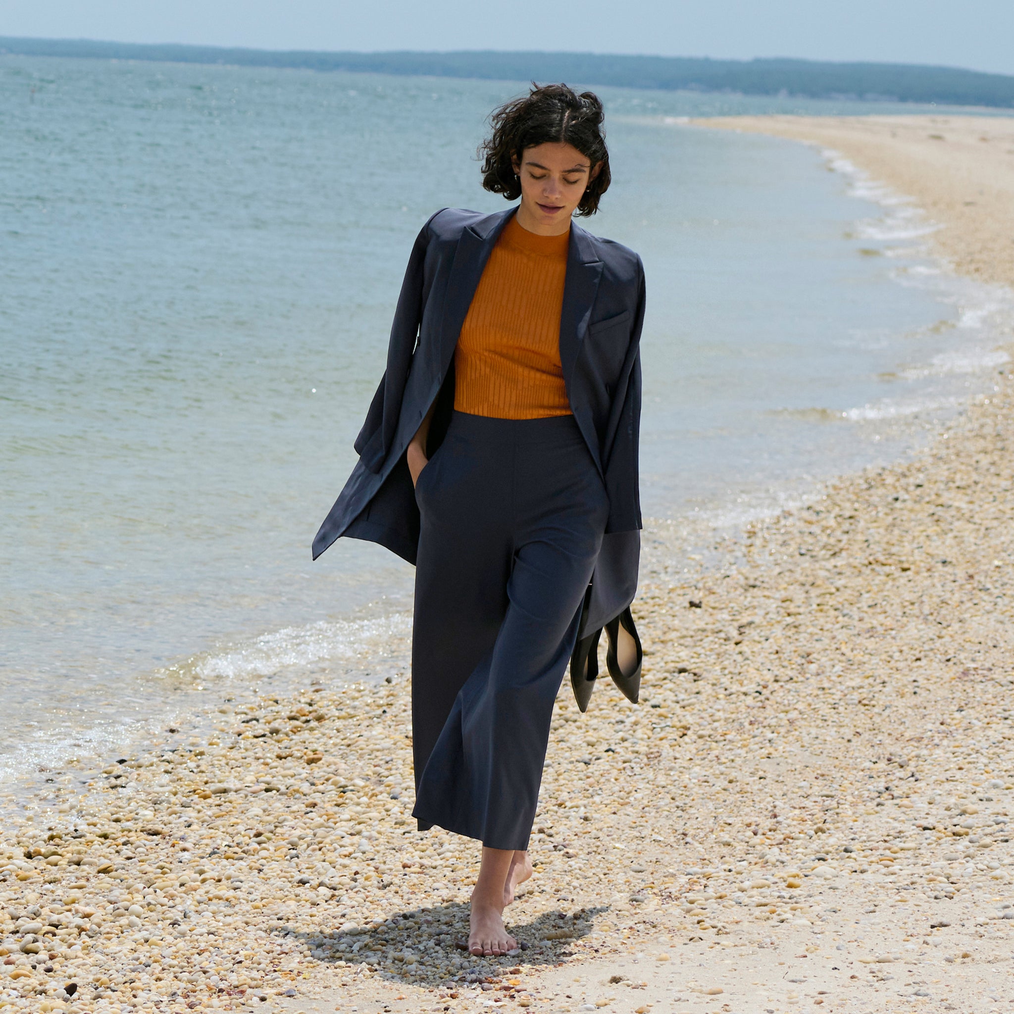 front image of a woman on the beach wearing the gwynne dress in cool charcoal as a jacket