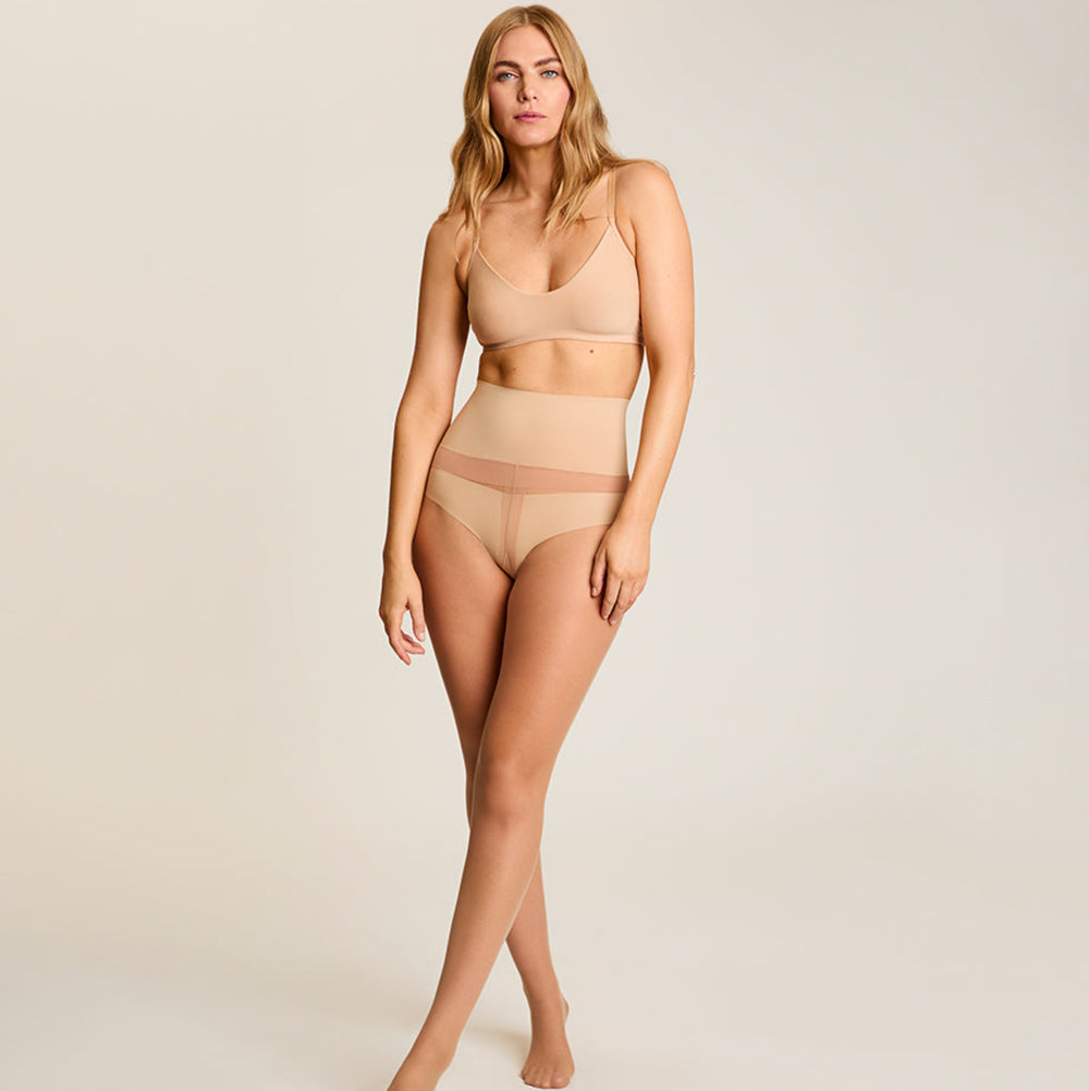 Woman wearing beige lingerie on a plain background