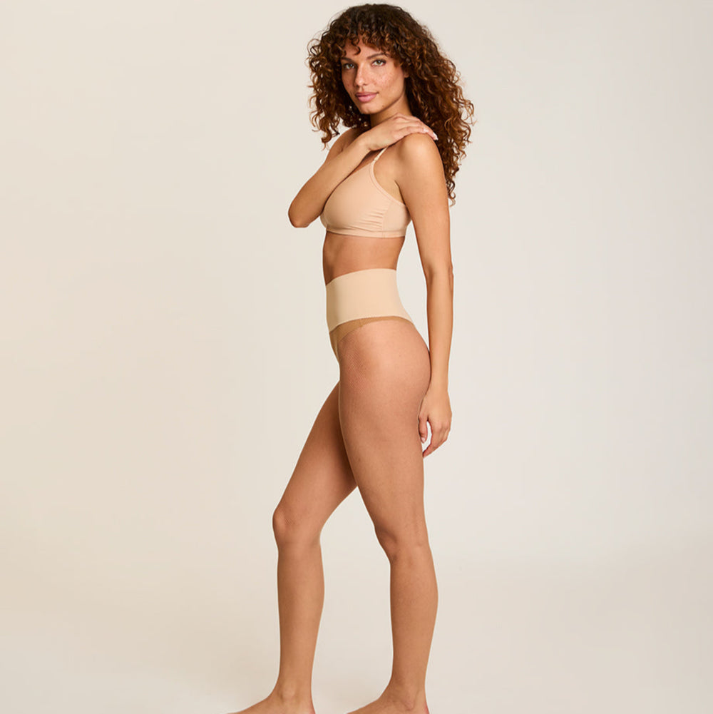 Woman wearing a beige set against a plain background
