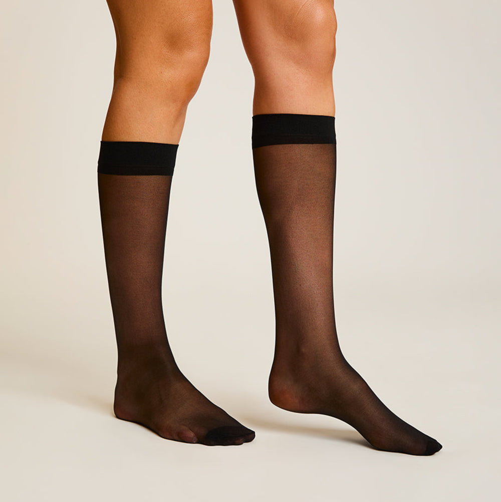 Black sheer stockings worn by a person on a beige background