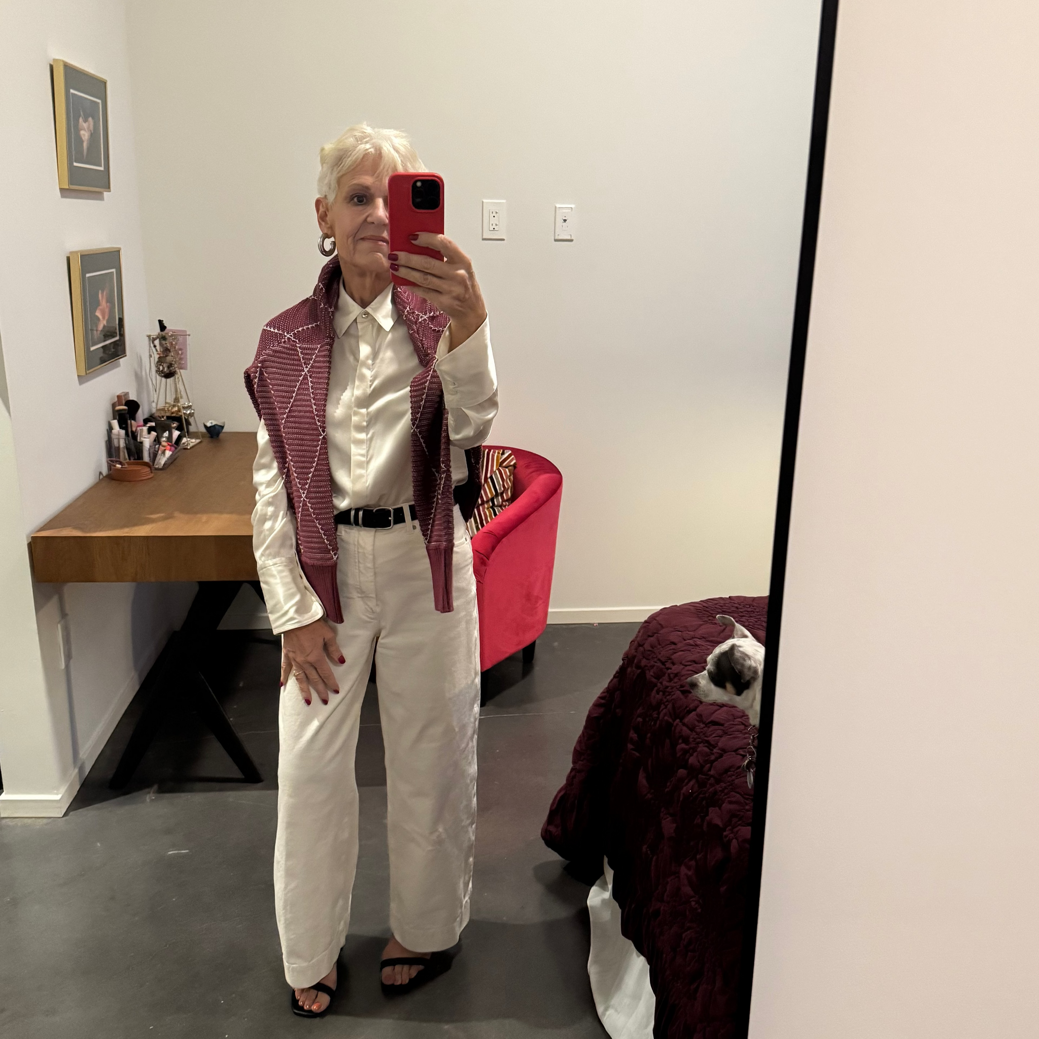 Person taking a mirror selfie in a room with a desk and chair.