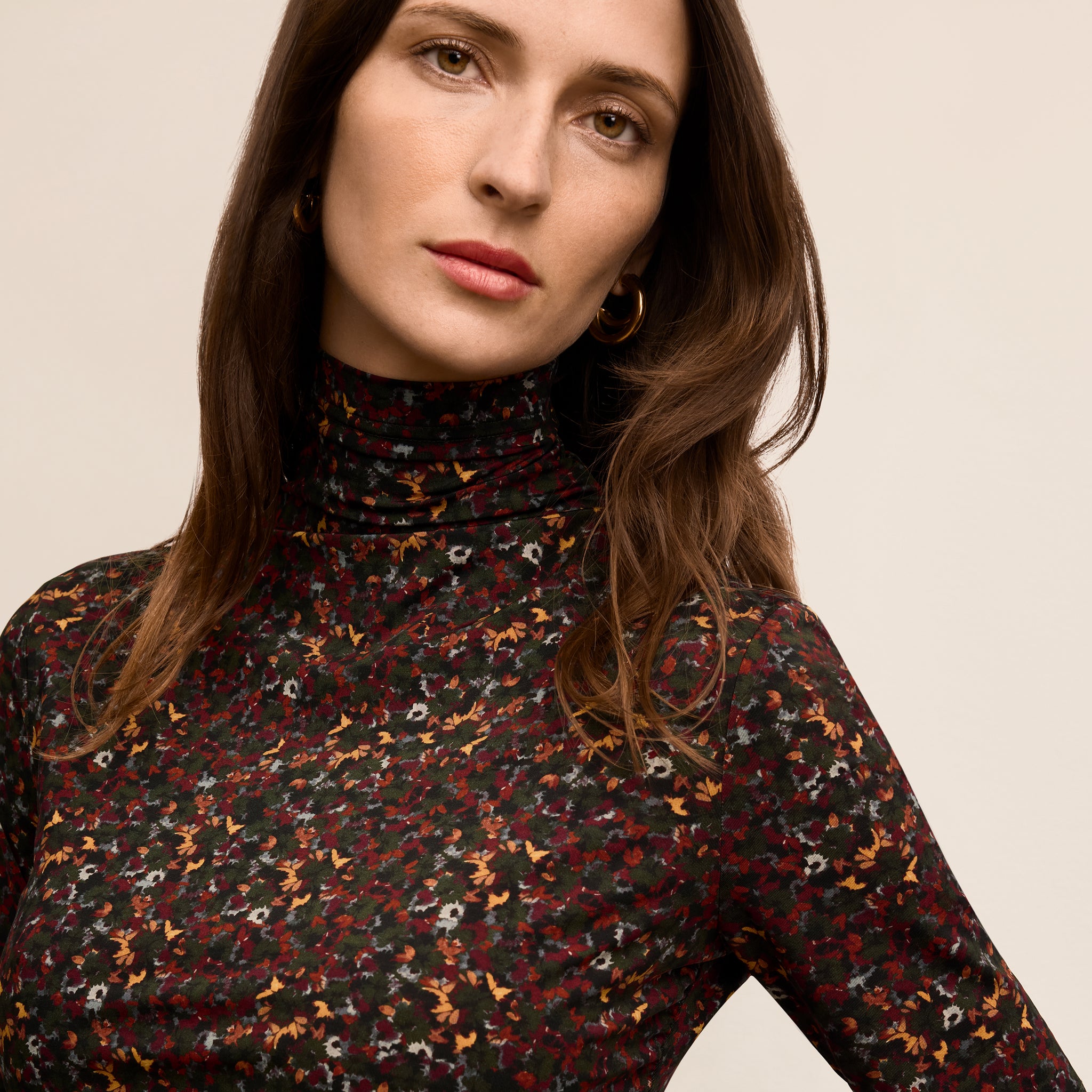 Woman wearing a patterned turtleneck sweater against a neutral background