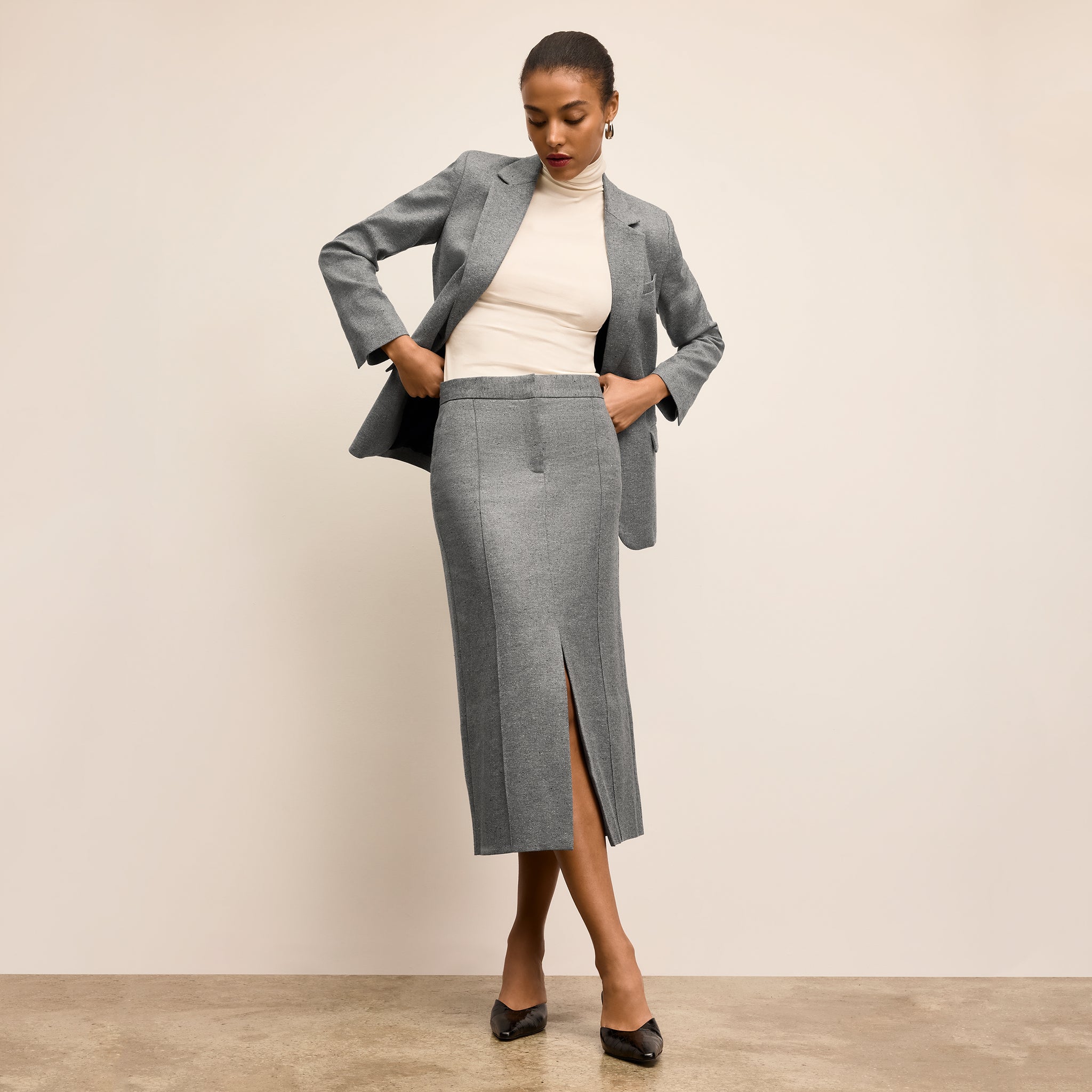 Woman wearing a gray suit with a white top on a beige background