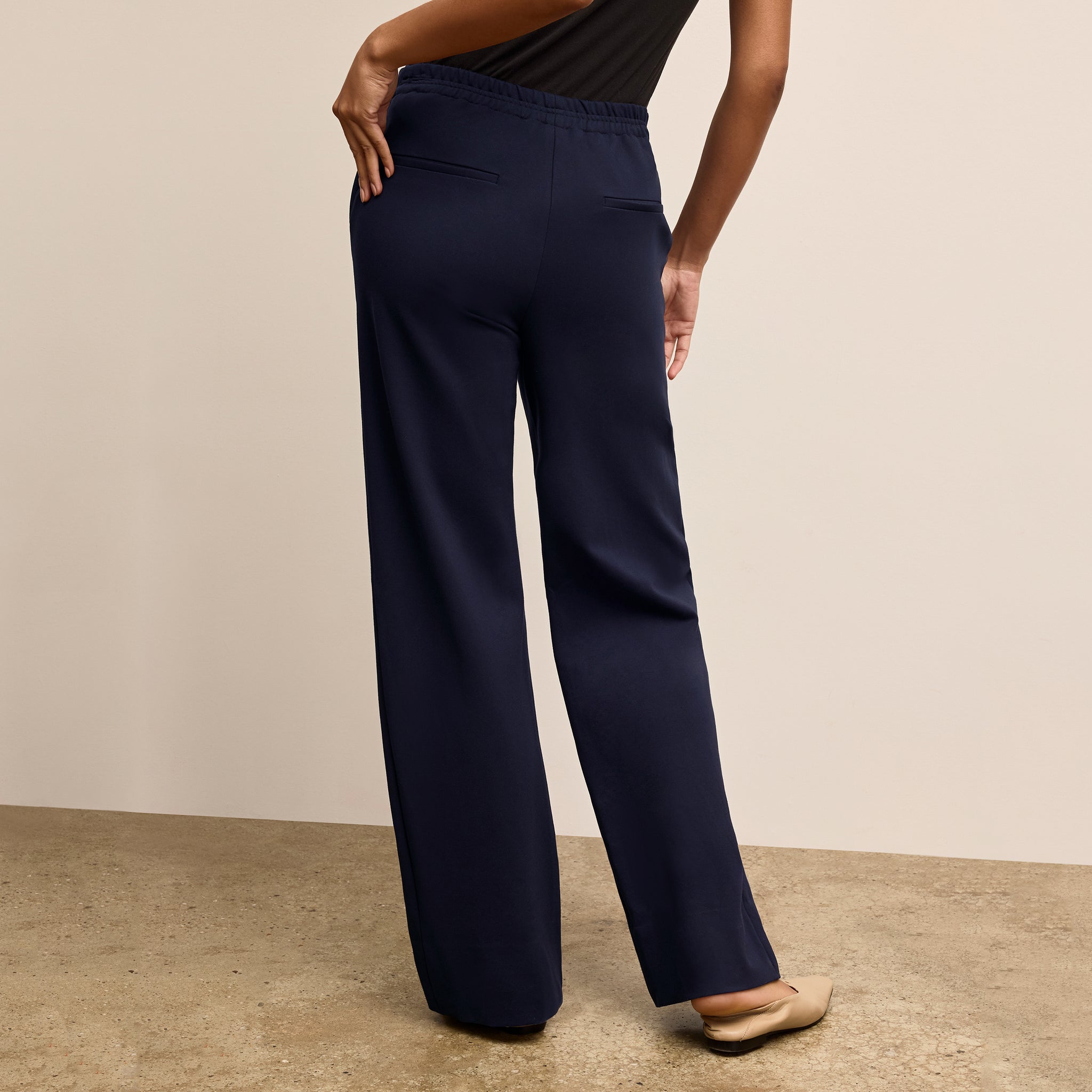 Navy blue pants worn by a person on a beige background