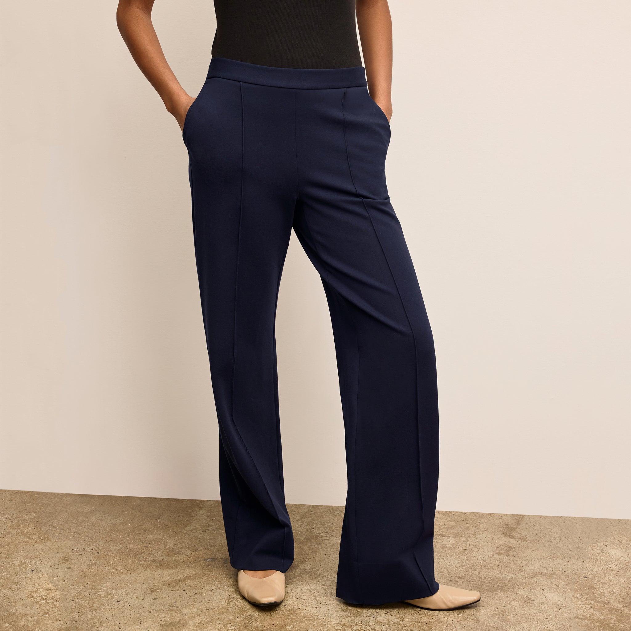 Navy blue pants worn by a person on a beige background 